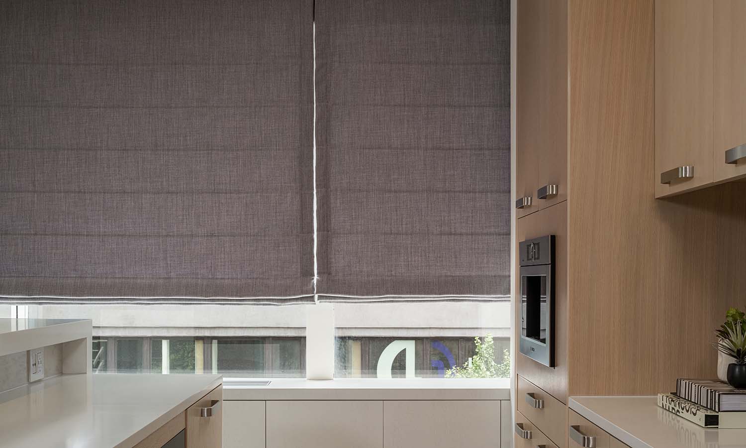 Motorized Roman shades over a window in a modern kitchen