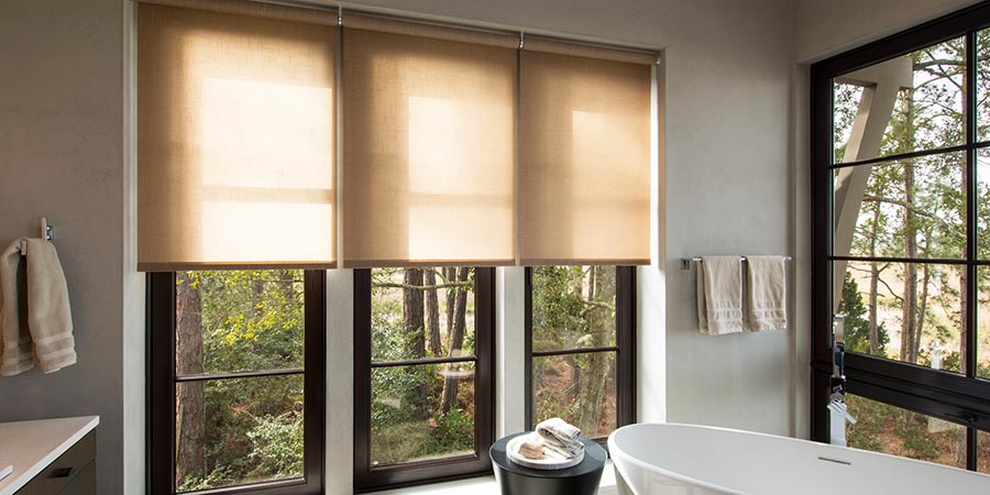 Bathroom with large windows featuring beige automated roller shades