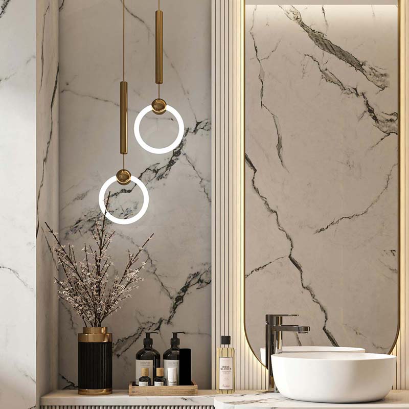 A modern farmhouse style home with picture windows at night with warm lighting inside where a kitchen and dining room are visible though the windows. 