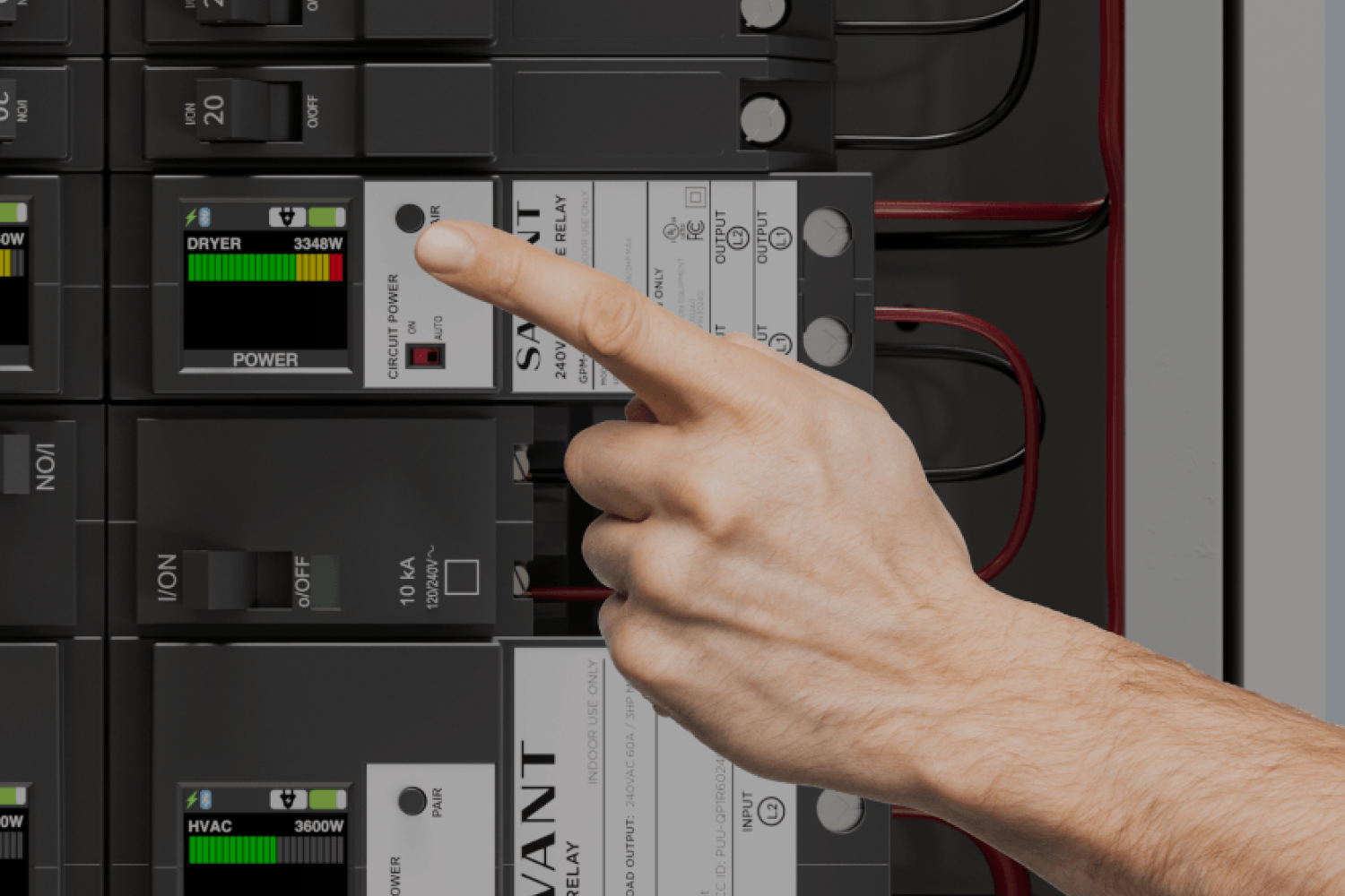 Hand pointing at a circuit breaker panel with digital displays